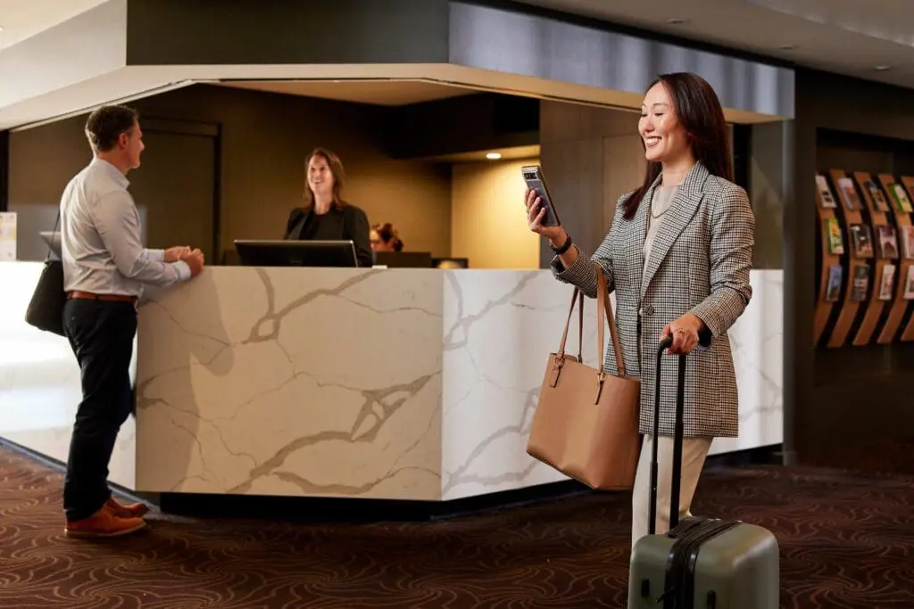 Commercial photography featuring corporate guests checking in at a modern hotel front desk reception.